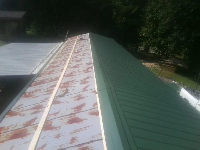 Old rusted panels beside newly installed green metal roofing — Wind Damage Roof Repair by Roofing Brothers in Washington Navy Yard