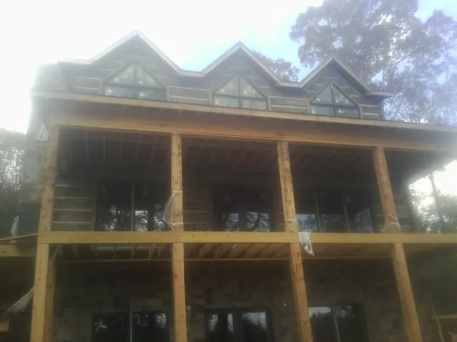 Dormers and porch framing on a large log home under construction — Roof Coating work by our crew in Washington Navy Yard