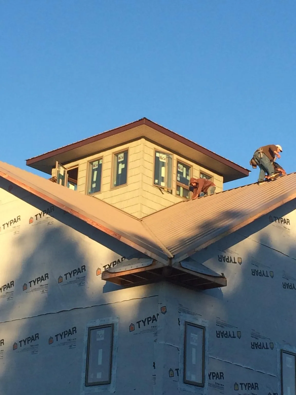 Roofers working around a rooftop cupola on a new metal roof at sunset — Roof Waterproofing in Washington Navy Yard by Roofing Brothers